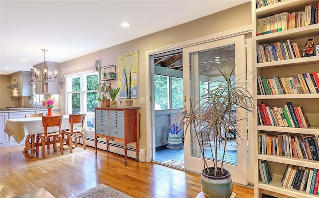 dining space featuring a baseboard radiator, healthy amount of natural light, light wood-style flooring, a chandelier, and recessed lighting
