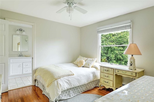 bedroom featuring hardwood / wood-style floors, a sink, ensuite bath, and ceiling fan