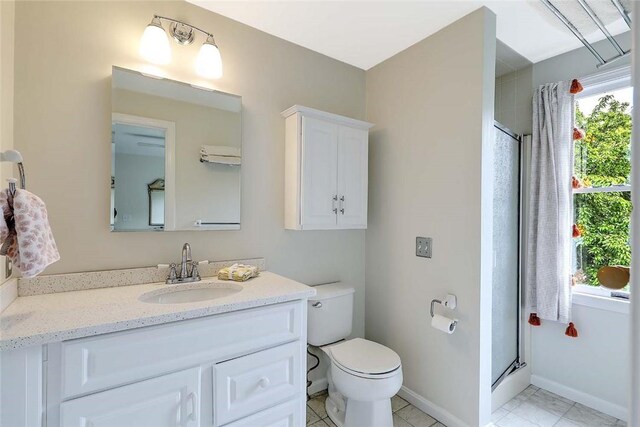 full bath featuring a stall shower, vanity, toilet, baseboards, and tile patterned floors
