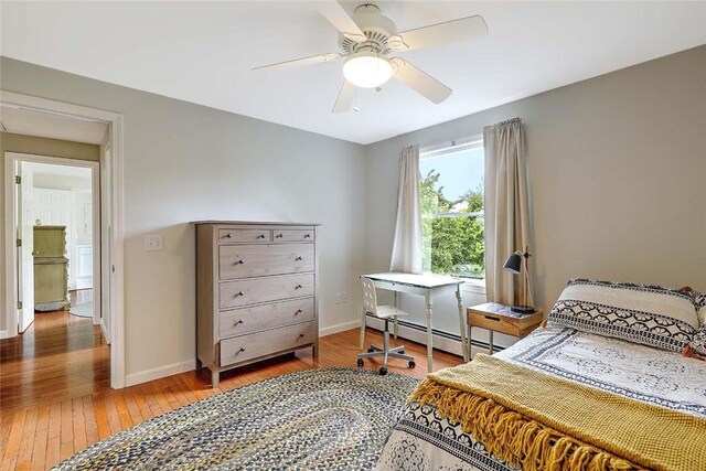 bedroom with baseboard heating, hardwood / wood-style floors, baseboards, and ceiling fan