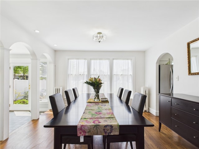 135 Cypress St, Providence, RI 02906 - dining area featuring radiator, arched walkways, and dark wood-style floors