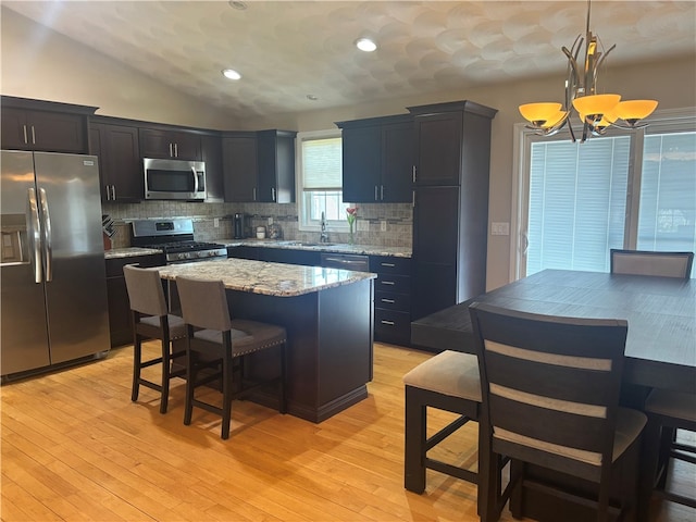 kitchen featuring a kitchen island, appliances with stainless steel finishes, a chandelier, and backsplash