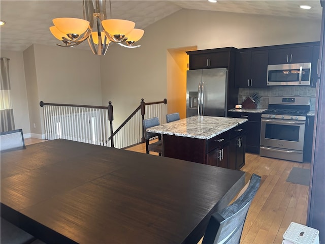 kitchen featuring lofted ceiling, recessed lighting, a chandelier, a kitchen island, and stainless steel appliances