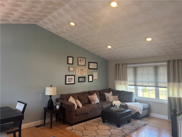living area featuring visible vents, baseboards, lofted ceiling, and wood-type flooring