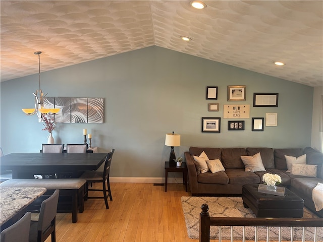 living area featuring lofted ceiling, recessed lighting, baseboards, light wood finished floors, and an inviting chandelier