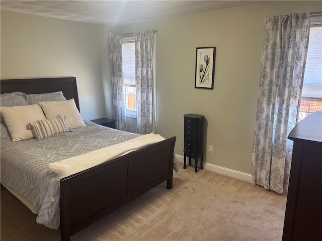bedroom with baseboards, multiple windows, and light carpet