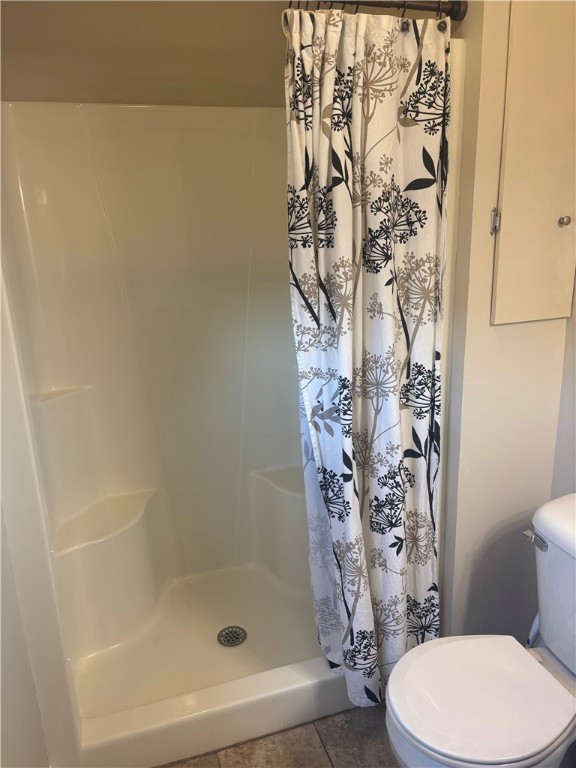 full bath featuring toilet and a stall shower