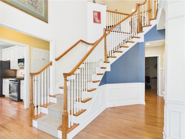 6 Yarmouth Cir S, Kingstown, RI 02879 - stairs featuring a wainscoted wall, a towering ceiling, and wood finished floors