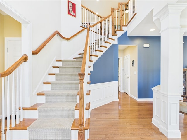 6 Yarmouth Cir S, Kingstown, RI 02879 - stairway featuring a wainscoted wall, wood finished floors, ornate columns, and a high ceiling
