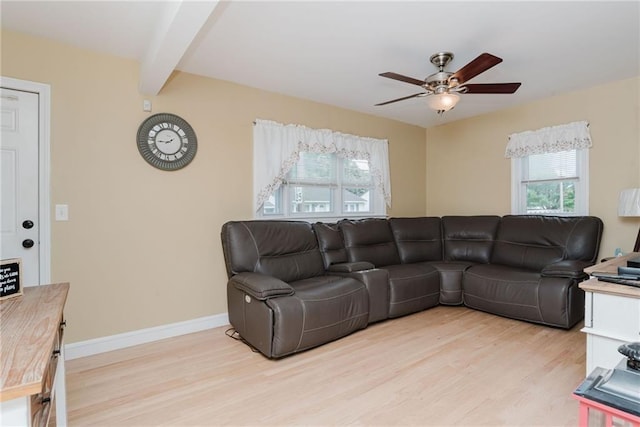 living area featuring light wood finished floors, baseboards, ceiling fan, and beam ceiling