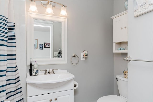 bathroom with curtained shower, vanity, and toilet