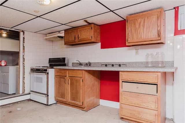 kitchen featuring a paneled ceiling, white gas range, washer / dryer, and a sink