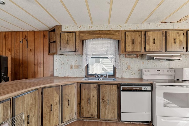 kitchen with under cabinet range hood, white appliances, a sink, and brown cabinets