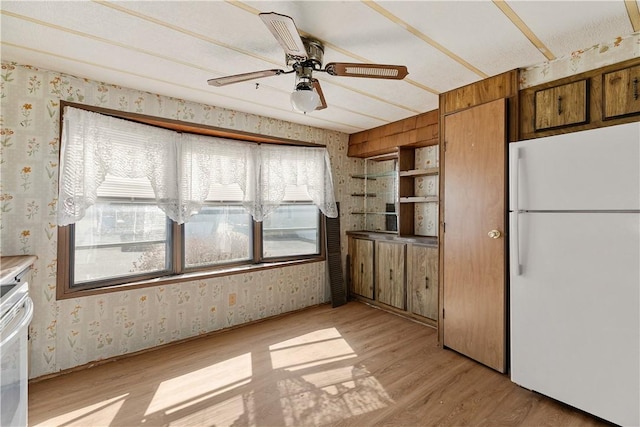 kitchen with freestanding refrigerator, wallpapered walls, ceiling fan, brown cabinets, and light wood-type flooring