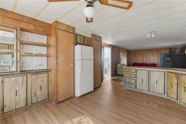 kitchen featuring freestanding refrigerator, wood walls, visible vents, and light wood-style floors