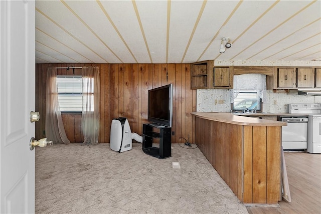 kitchen with under cabinet range hood, dishwashing machine, brown cabinets, and a healthy amount of sunlight