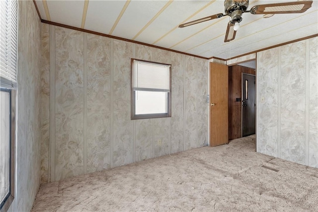 empty room featuring crown molding, a ceiling fan, and carpet