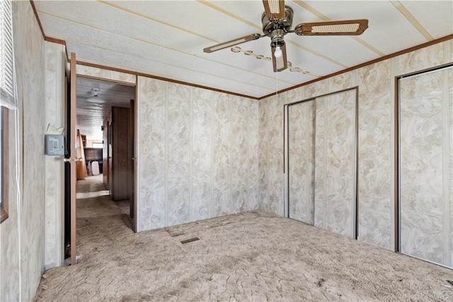 carpeted empty room with a ceiling fan and ornamental molding