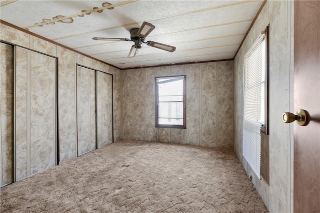 unfurnished bedroom featuring crown molding, a textured ceiling, ceiling fan, and carpet floors