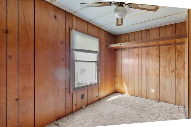 empty room featuring wooden walls, ceiling fan, and carpet floors