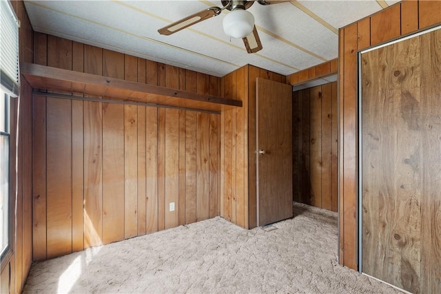 unfurnished bedroom featuring wood walls, ceiling fan, and carpet floors