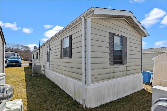 view of side of home with central AC unit and a lawn