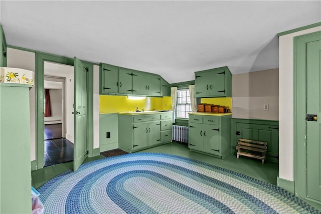 kitchen with green cabinets, light countertops, radiator heating unit, and a sink