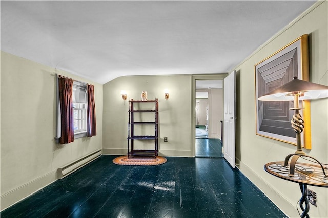 empty room with a baseboard heating unit, baseboards, wood finished floors, and vaulted ceiling