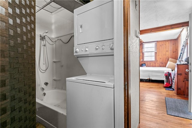 ensuite bathroom with stacked washer and clothes dryer, ensuite bath, shower / bathing tub combination, and wood-type flooring