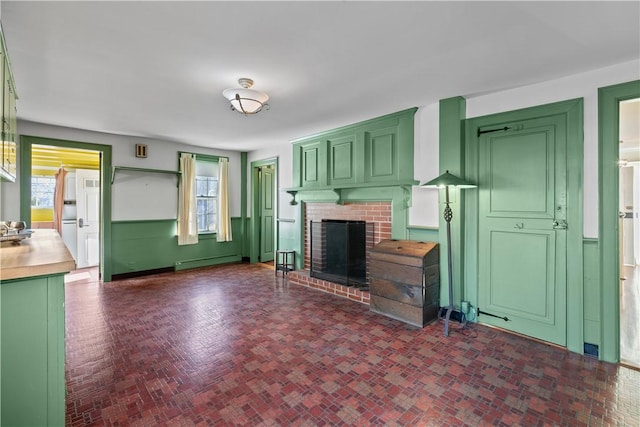 unfurnished living room featuring brick floor, a baseboard radiator, and a brick fireplace