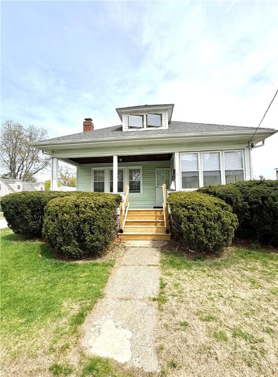 bungalow with a porch, a chimney, and a front yard