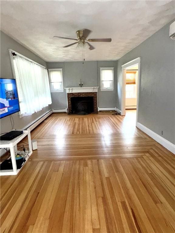 unfurnished living room featuring wood finished floors, a ceiling fan, a brick fireplace, baseboards, and a baseboard heating unit