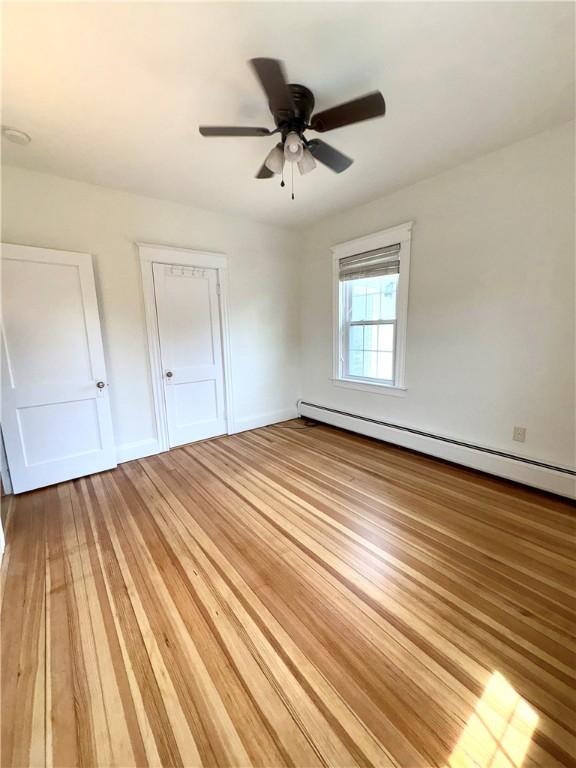 unfurnished bedroom with baseboards, light wood-style floors, baseboard heating, and ceiling fan