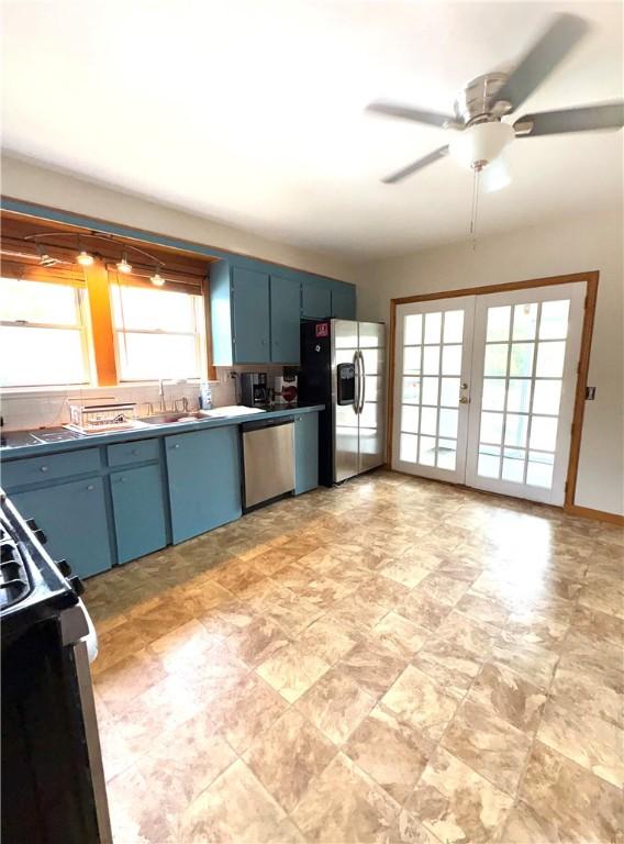 kitchen with stone finish flooring, stainless steel appliances, ceiling fan, and blue cabinetry