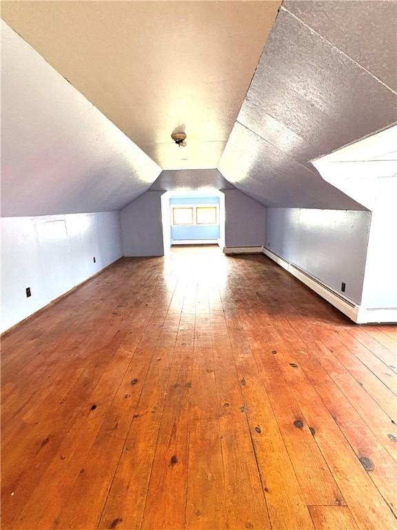 bonus room with a baseboard radiator, lofted ceiling, and wood-type flooring