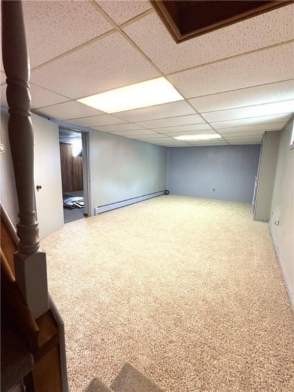 finished basement featuring carpet flooring, a drop ceiling, and a baseboard radiator