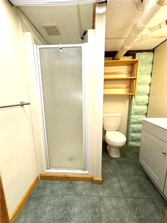 bathroom with a stall shower, toilet, visible vents, tile patterned flooring, and vanity