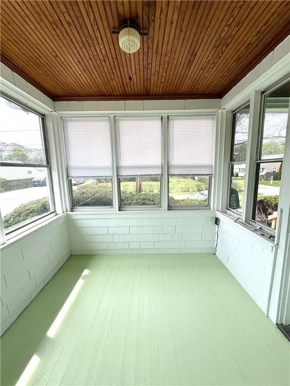 unfurnished sunroom with plenty of natural light, wood-type flooring, and wooden ceiling