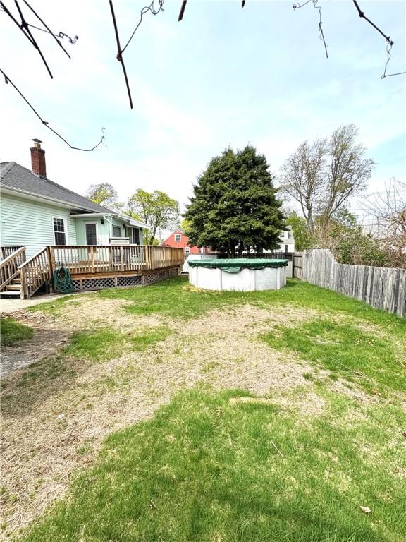 view of yard with a deck, a fenced in pool, and fence