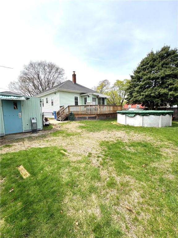view of yard featuring a deck, an outdoor structure, a covered pool, and a storage unit