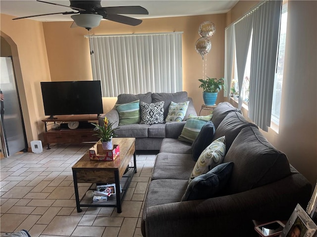 living area with a ceiling fan and arched walkways