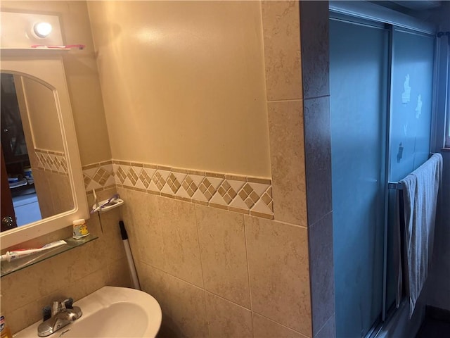 bathroom with a sink, wainscoting, and tile walls
