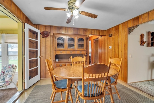 dining room featuring light carpet, wood walls, and ceiling fan