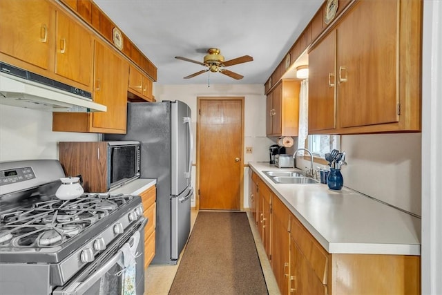 kitchen featuring a ceiling fan, a sink, gas range, under cabinet range hood, and light countertops