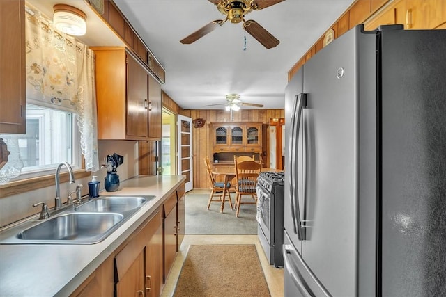 kitchen featuring stainless steel appliances, a ceiling fan, a sink, light countertops, and brown cabinets