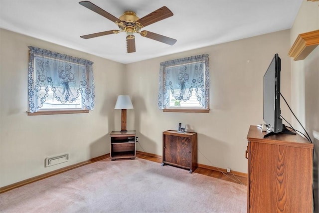 living area featuring baseboards, a wealth of natural light, carpet flooring, and ceiling fan