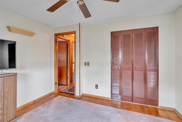 unfurnished bedroom featuring a closet, baseboards, a ceiling fan, and wood finished floors
