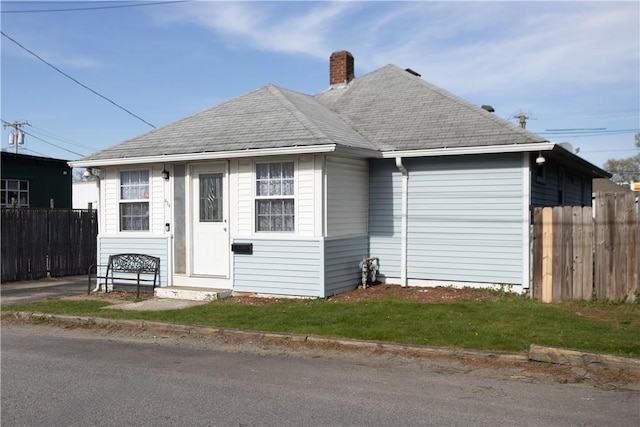 bungalow featuring a chimney and fence