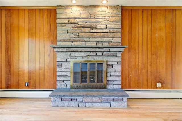 details with a baseboard heating unit, wooden walls, and a fireplace