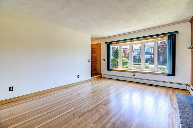 empty room featuring light wood-type flooring, baseboards, and a baseboard radiator